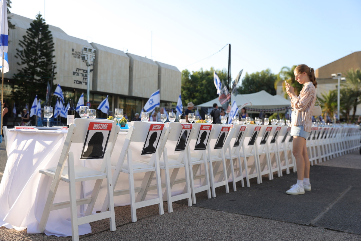 Накрытый в центре Тель-Авива обеденный стол для заложников ХАМАС. Инсталляция символизирует, что похищенных израильтян ждут домой на традиционную трапезу в шаббат. Фото: ABIR SULTAN/EPA