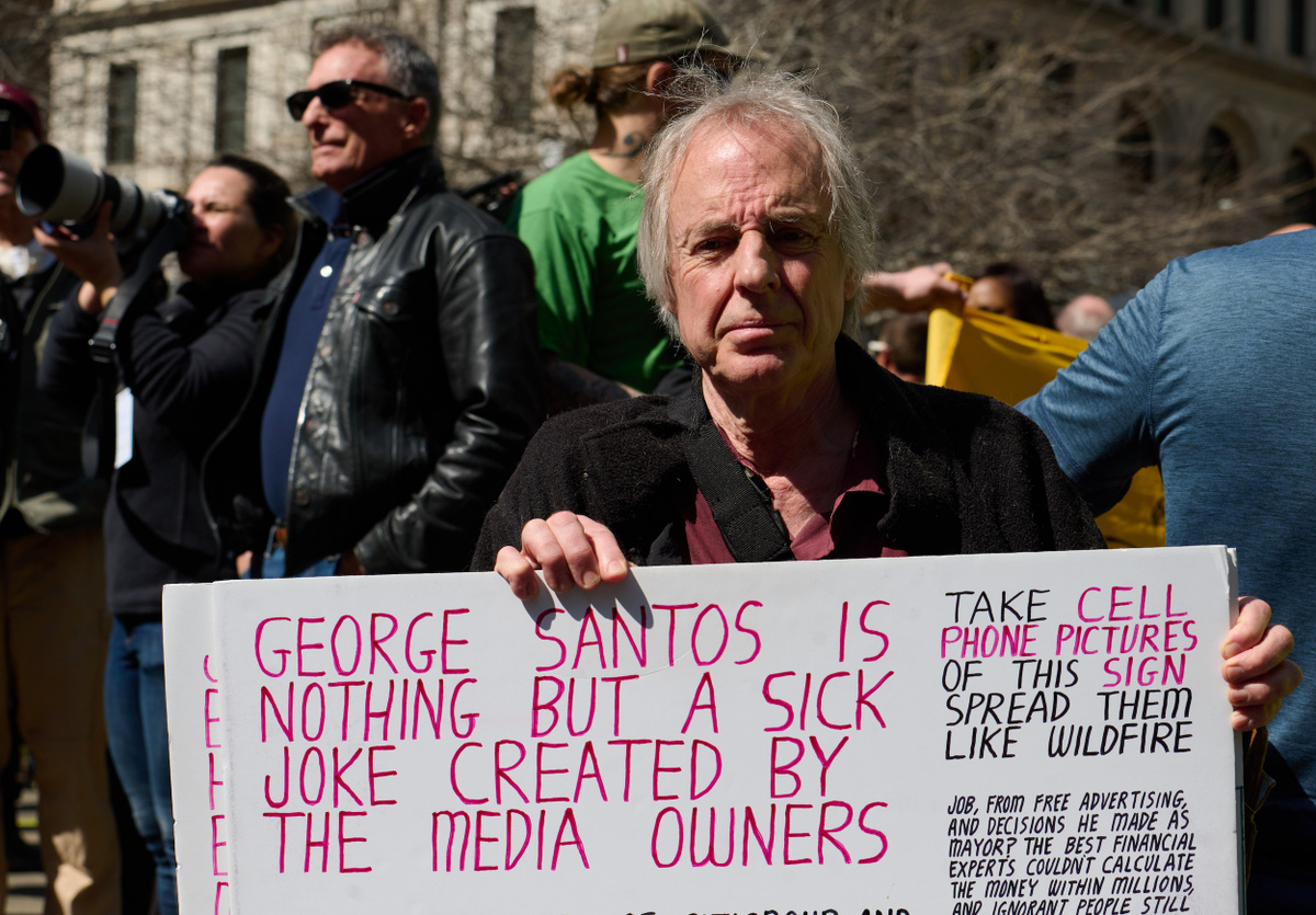 Участник протеста с плакатом: «Джордж Сантос — всего лишь жестокая шутка, созданная владельцами СМИ». Zuma/TASS
